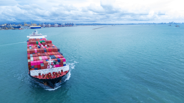 front view Cargo Container ship with contrail in the ocean ship carrying container and running By Bluesandisland